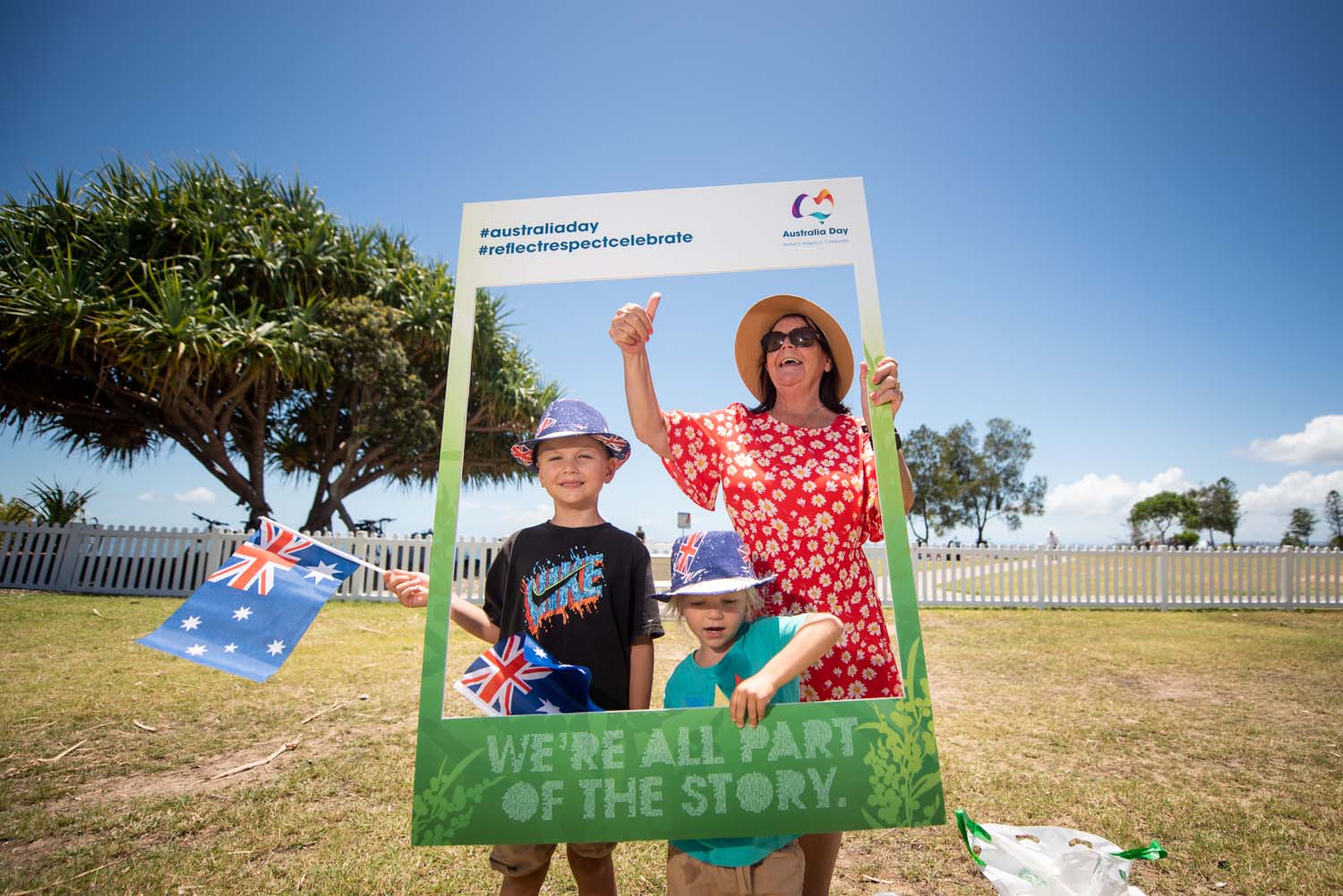 Adult and two children holding an Australia Day photo booth frame.