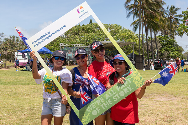 Four women in Australia Day branded hats holding Australian flags.